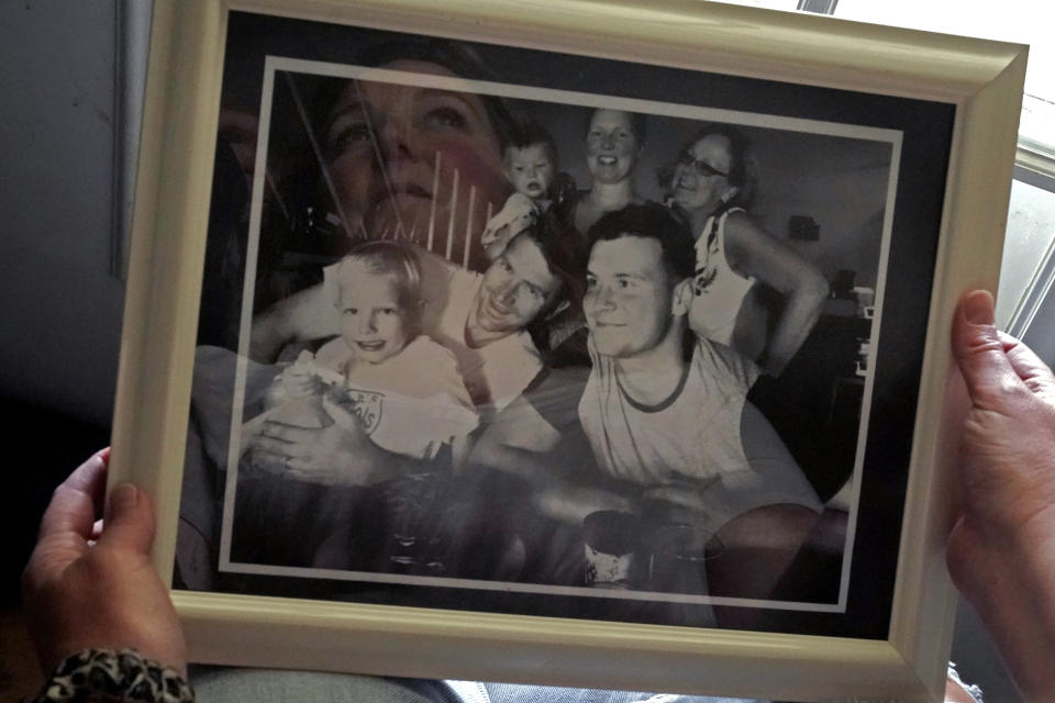 Briana Garton looks at a family photo showing her late brother, Taylor Ware, foreground right, as she talks about his 2019 death, Tuesday, June 6, 2023, at her home near Hale, Mo. “It was like that was his body’s own fault, that it wasn’t the police’s fault,” Garton, said of the autopsy ruling that Ware died of natural causes. (AP Photo/Charlie Riedel)