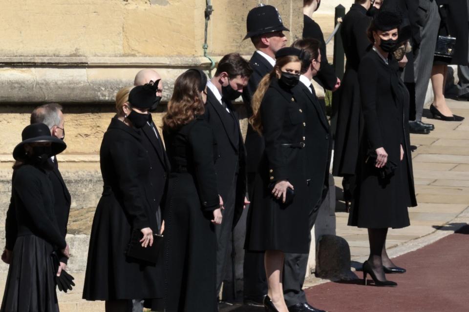 Kate, Duchess of Cambridge, and other masked family members stand along a road on the grounds of Windsor Castle.