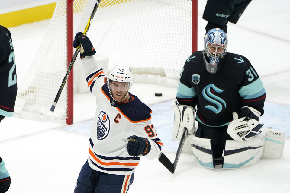 Edmonton Oilers center Connor McDavid, left, reacts after scoring on Seattle Kraken goaltender Philipp Grubauer (31) during the third period of an NHL hockey game Friday, Dec. 3, 2021, in Seattle. (AP Photo/Elaine Thompson)