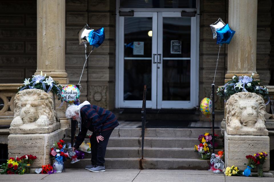 A man places a small statue outside of the main entrance to the Anamosa State Prison, on Wednesday, March 24, 2021, a day after a nurse and correctional officer were killed while on duty, in Anamosa, Iowa. 