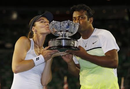 Martina Hingis (L) of Switzerland and Leander Paes of India kiss their trophy after defeating Kristina Mladenovic of France and Daniel Nestor of Canada to win their mixed doubles final match at the Australian Open 2015 tennis tournament in Melbourne February 1, 2015. REUTERS/Issei Kato