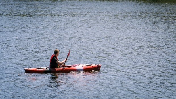 A young man wearing a life jacket paddles in his kayak on the Gatineau side of the Ottawa River on May 15, 2021.  