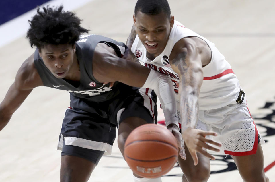 Washington State guard Noah Williams, left, and Arizona guard James Akinjo (13) reach for the ball during the first half of an NCAA college basketball game Thursday, Feb. 25, 2021, in Tucson, Ariz. (Kelly Presnell/Arizona Daily Star via AP)