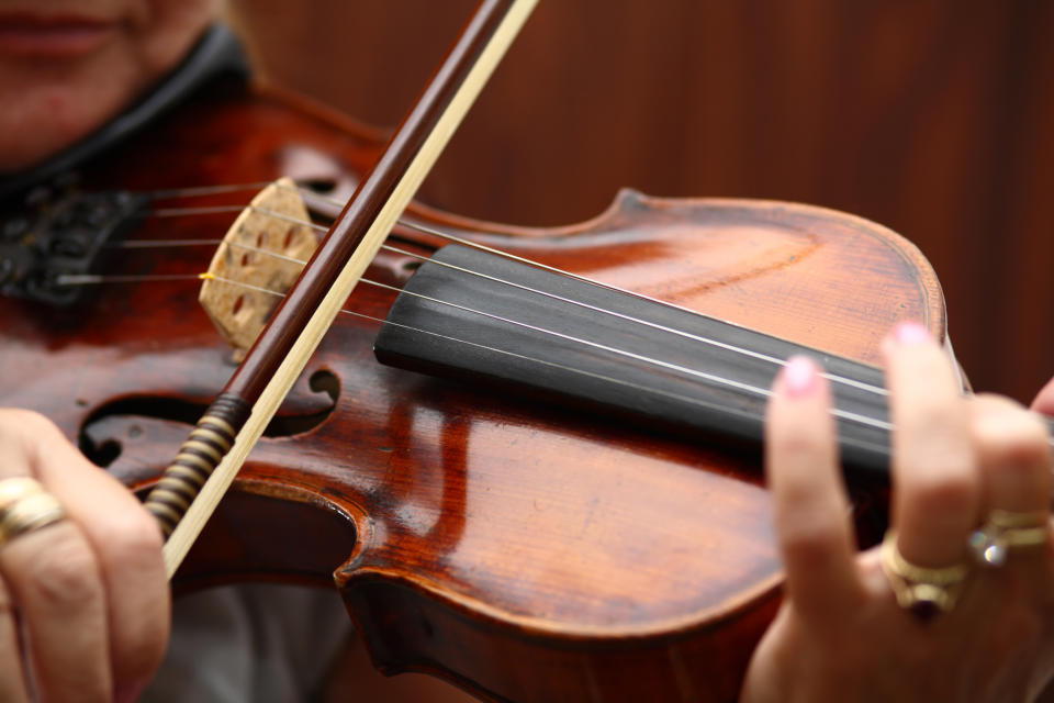 Close-up of a person playing a violin, focusing on the instrument and bow in their hands