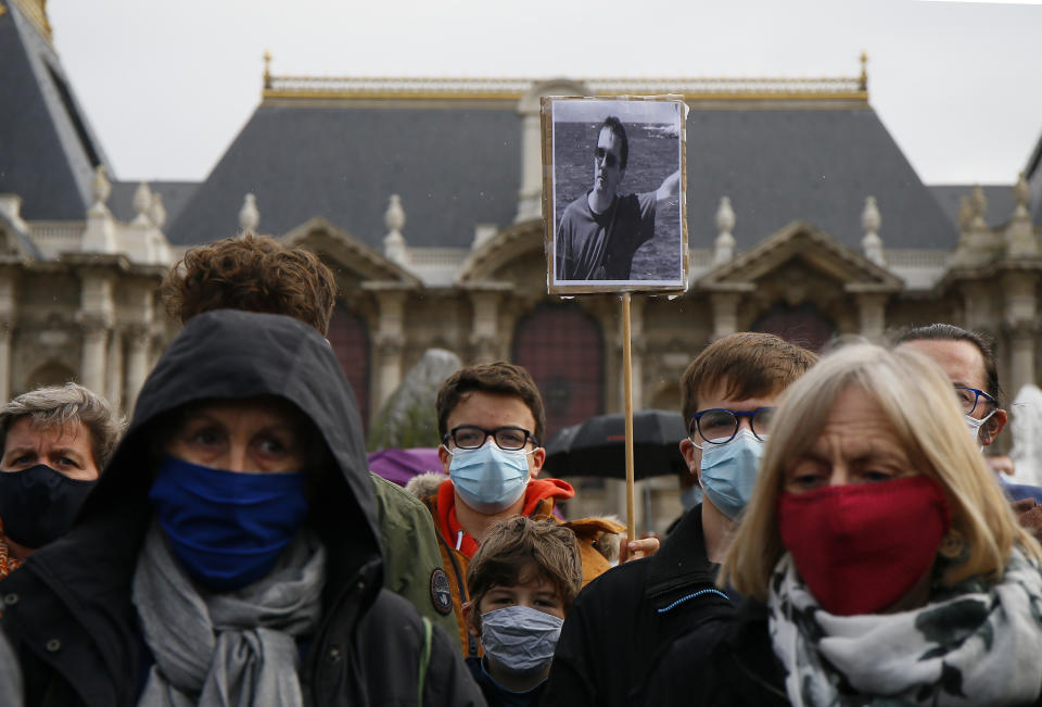 A person holds up a a portrait of Samuel Paty as they gather on Republique square in Lille, northern France, Sunday Oct. 18, 2020. Demonstrators in France on Sunday took part in gatherings in support of freedom of speech and in tribute to a history teacher who was beheaded near Paris after discussing caricatures of Islam’s Prophet Muhammad with his class. (AP Photo/Michel Spingler)