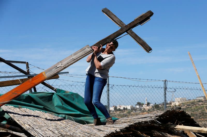 A Palestinian woman retrieves a wooden cross after an Israeli machinery bulldozed a land in the town of Beit Jala, in the Israeli-occupied West Bank