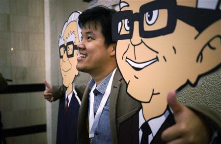 A Berkshire Hathaway shareholder poses with caricatures of CEO Warren Buffett (L) and Vice-Chairman Charlie Munger at a welcome cocktail reception in Omaha, Nebraska May 2, 2014, in the lead up to the Berkshire Hathaway annual meeting on May 3, 2014. REUTERS/Rick Wilking