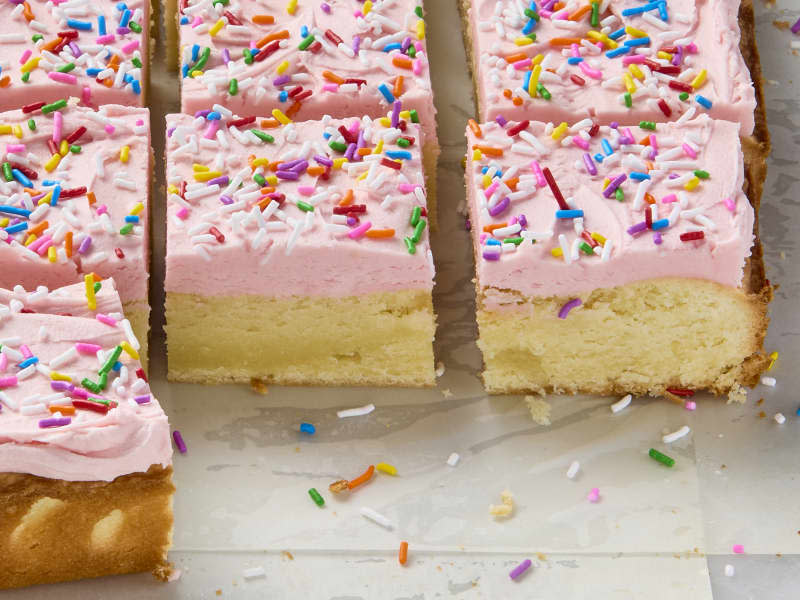 A lower angle of sour cream bar cookies with pink frosting and rainbow sprinkles