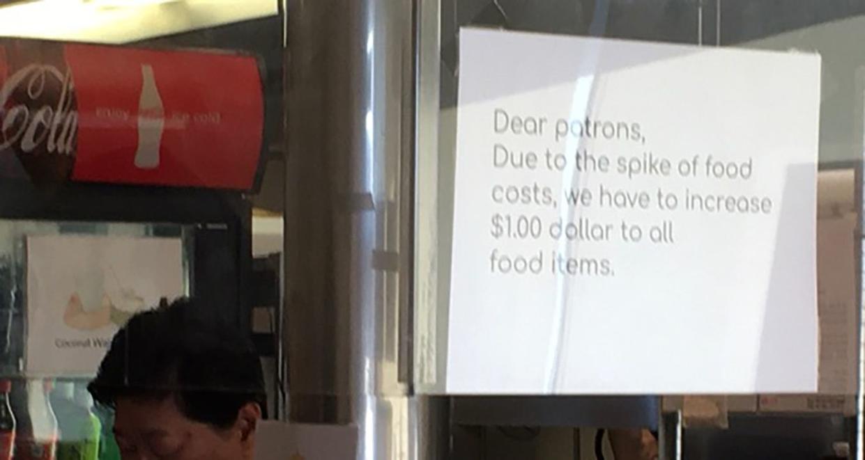 Sign on door saying "Inflation felt at Pho restaurant by $1 increase to food prices"