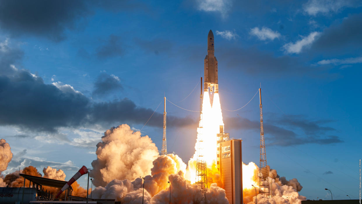  an ariane 5 rocket launches from french guiana in july 2021, rising into a darkening sky atop a widening pillar of flame 