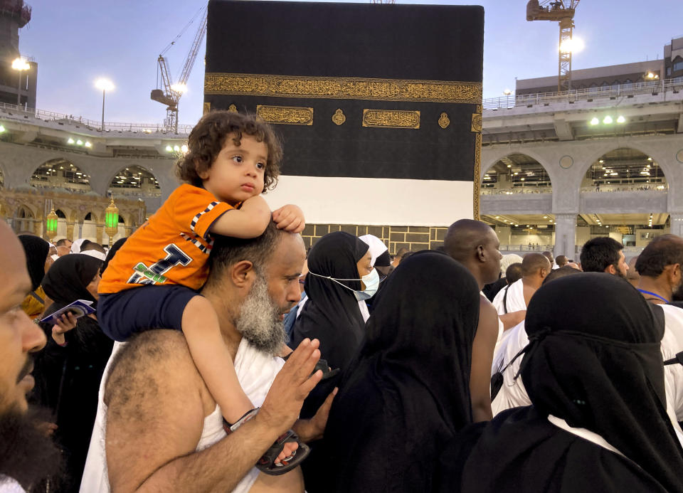 A Muslim pilgrim carries his son as he circumambulates around the Kaaba, the cubic building at the Grand Mosque, in the Saudi Arabia's holy city of Mecca, Tuesday, July 5, 2022. Saudi Arabia is expected to receive one million Muslims to attend Hajj pilgrimage, which will begin on July 7, after two years of limiting the numbers because coronavirus pandemic. (AP Photo/Amr Nabil)