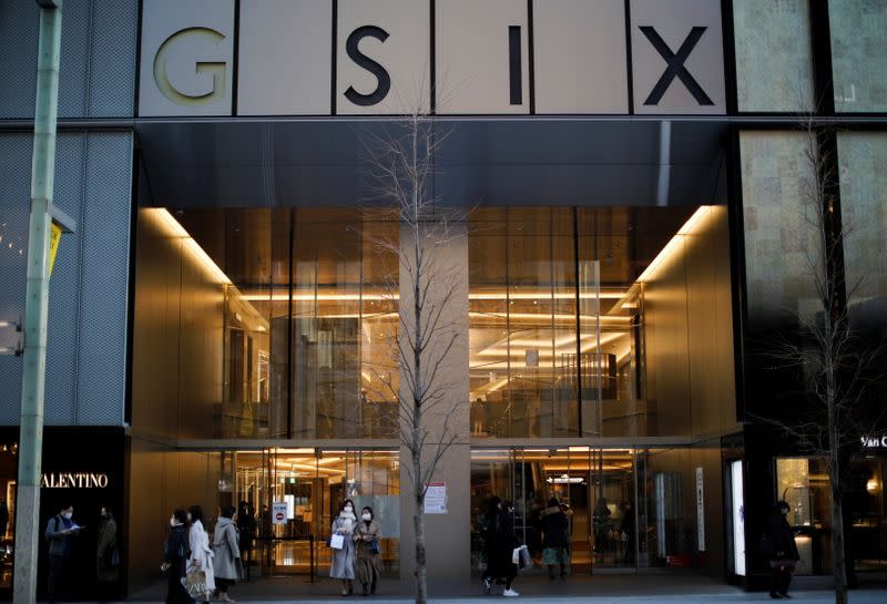 People wearing protective face masks walk in front of Ginza Six, a luxury shopping complex, in Tokyo