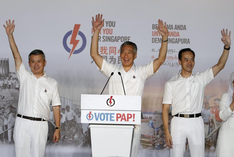 Singapore's Prime Minister and Secretary-General of the People's Action Party Lee Hsien Loong (C) thanks supporters with his team after the general election results at a stadium in Singapore September 12, 2015. Singapore's ruling party romped to a strong election victory on Friday and was on course to increase its share of the vote and seat tally as it brushed off an opposition challenge in the city state's most hotly contested polls. REUTERS/Edgar Su