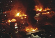 FILE - In this April 29, 1992 file photo, several buildings in a Boys Market shopping center are fully engulfed in flames before firefighters can arrive as rioting erupted in South-Central Los Angeles following the acquittal of four police officers in the videotaped beating of Rodney King. (AP Photo/Reed Saxon, File)