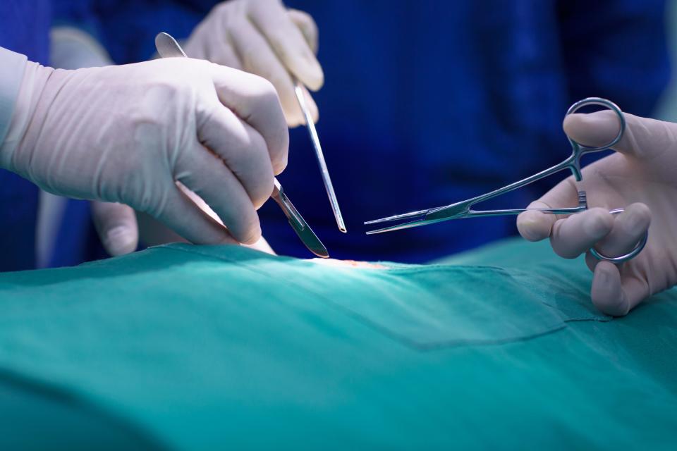 Hands of doctors performing surgery in hospital operating room.