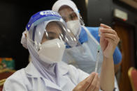 A nurse prepares a dose of the Pfizer vaccine against the coronavirus disease (COVID-19) for a secondary school student at a vaccine center in Shah Alam, Malaysia, Monday, Sept. 20, 2021. (AP Photo/Vincent Thian)