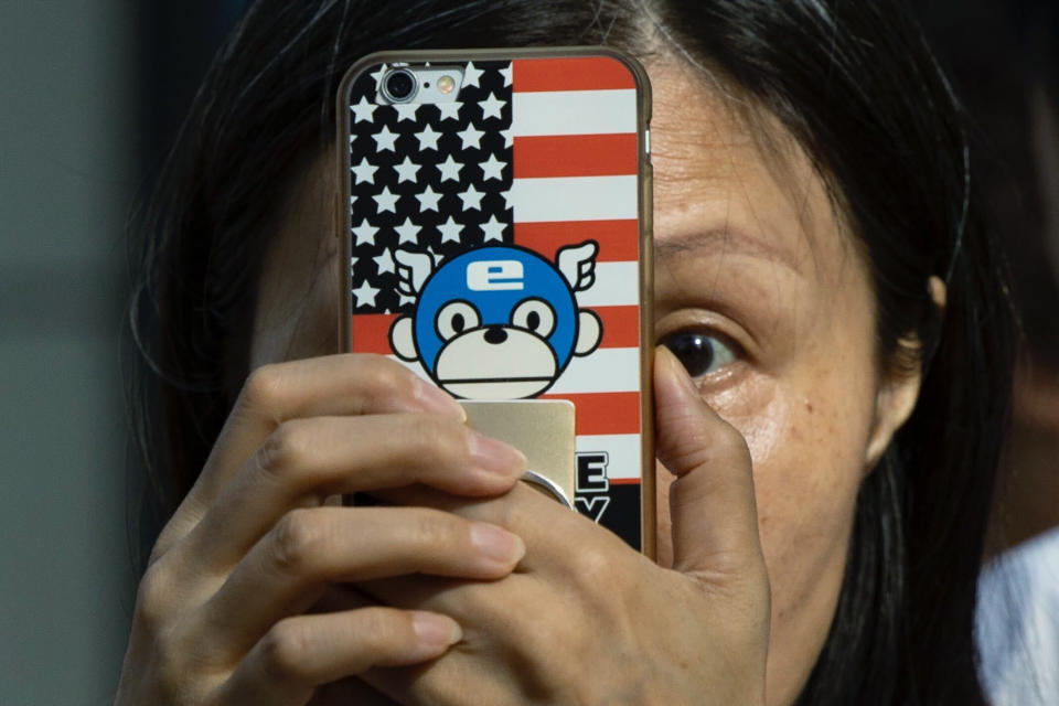 A woman takes a photo with a phone that has a United States flag themed cover outside the United States Consulate in Chengdu in southwest China's Sichuan province on Sunday, July 26, 2020. China ordered the United States on Friday to close its consulate in the western city of Chengdu, ratcheting up a diplomatic conflict at a time when relations have sunk to their lowest level in decades. (AP Photo/Ng Han Guan)