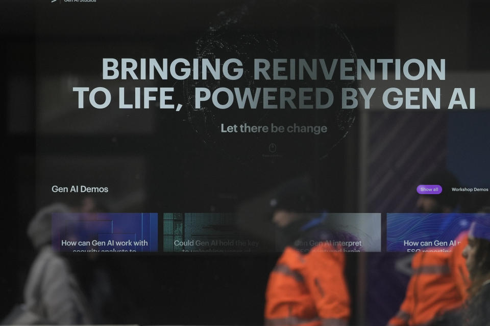 People reflected in a window of a building at the Davos Promenade with a slogan about AI alongside the World Economic Forum in Davos, Switzerland, Thursday, Jan. 18, 2024. The AI technology has taken a large and growing slice of attention in Davos, this year the theme of Artificial Intelligence "as a driving force for the economy and society" will get about 30 separate sessions. (AP Photo/Markus Schreiber)