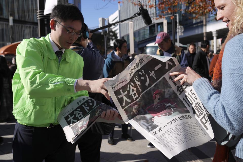 A staff distributes an extra edition of the Yomiuri Shimbun newspaper reporting on Shohei Ohtani to move to the Los Angeles Dodgers Sunday, Dec. 10, 2023, in Tokyo. Ohtani agreed to a record $700 million, 10-year contract with the Dodgers. (AP Photo/Eugene Hoshiko)