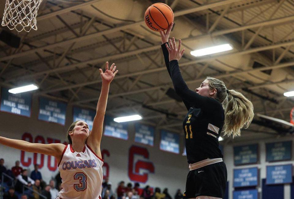 Independence Patriots Kamryn Kitchen, right, shoots past a block by Charlotte Catholic Cougars Kate Mcardle at Charlotte Catholic High School in Charlotte, N.C., on Tuesday, January 30, 2024.