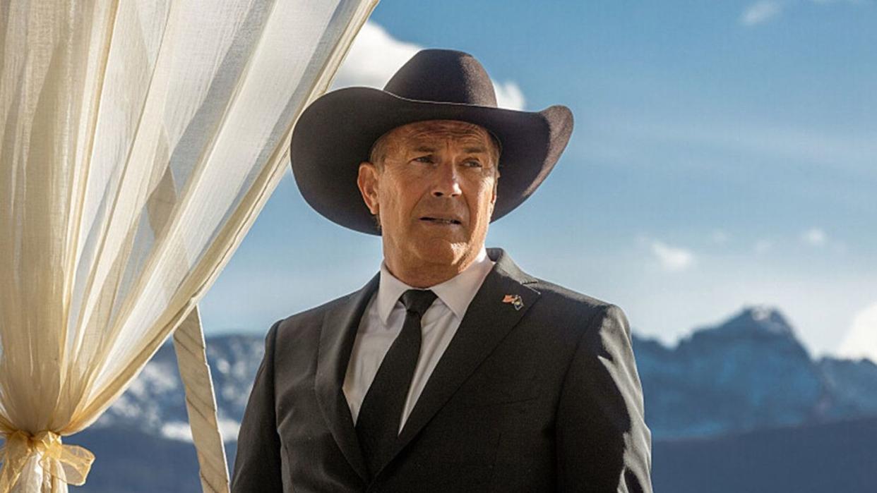 a man wearing a hat and standing in front of a white tent