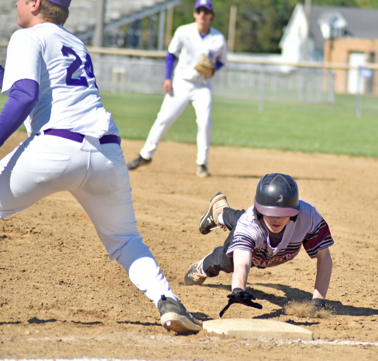 Union City's Ethan Neveraski dives safely back to first on an attempted pick off by Bronson. Bronson first baseman Carson Stevens awaits the throw.