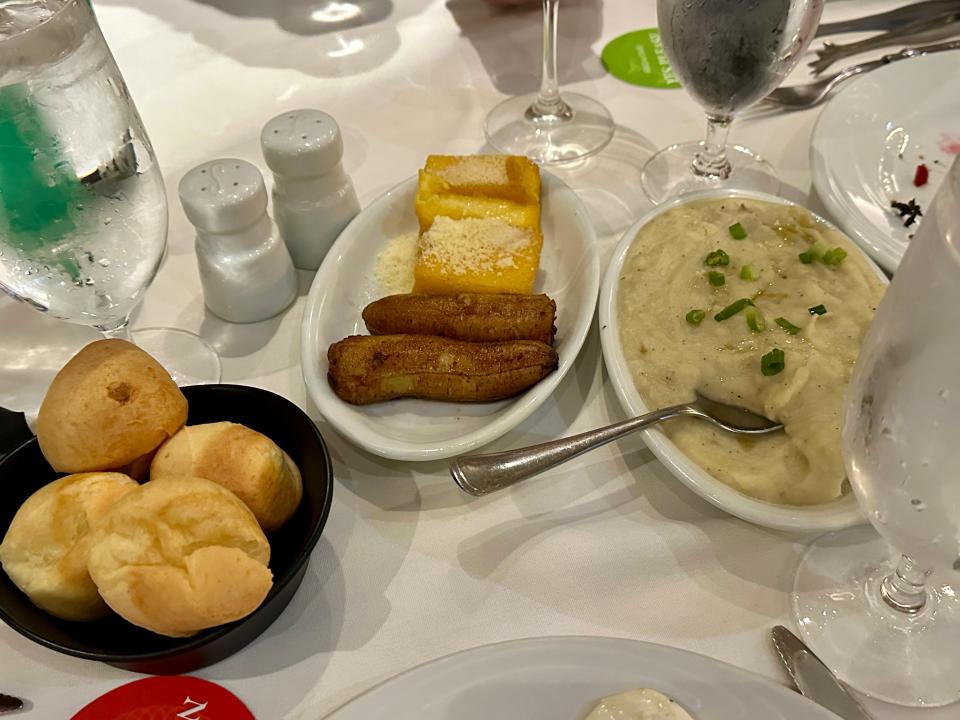 plates of bread, potatoes, and other side dishes at fogo de chao