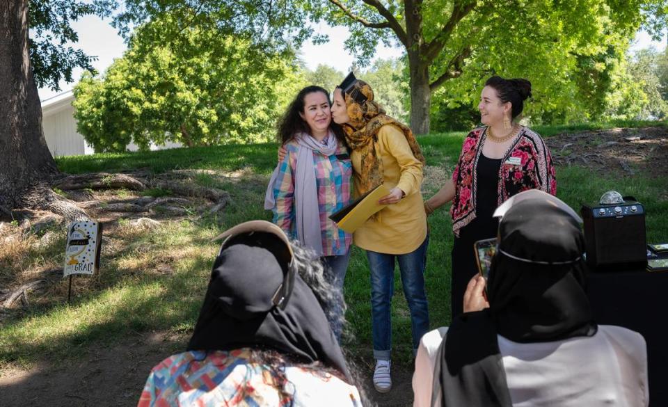 Estori Afzali, greets IRC business counselor Halima Mohammadi, left, and IRC senior education and health promoter Katharina Beeler, right, during a graduation ceremony at Davis Park in Modesto Calif., on Friday, July 1, 2022. Seventeen women refugees from Afghanistan are the first graduates of the International Rescue Committee and Modesto Junior College’s child care microenterprise development program for home child-care licensing.