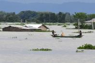 Villagers travel on a boat at the flood affected area of Gagalmari village in Morigaon district of Assam state on July 14, 2020. (Photo by BIJU BORO/AFP via Getty Images)