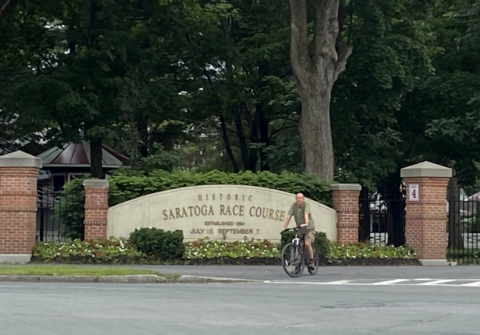 A bicyclist rides past the locked gates at the Saratoga Race Course in Saratoga Springs, N.Y., Thursday, July 16, 2020. A Saratoga season like no other is underway, with fans barred from attending the start of the 152nd meet in track history and most likely the entire 40 days of racing. (AP Photo/John Kekis)