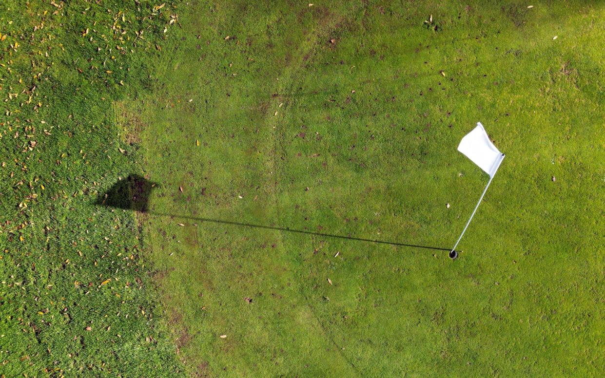 Aerial view of a golf flag and shadow on a putting green