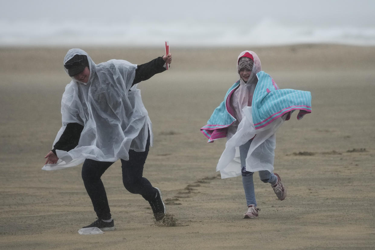 Beach combers run along the beach on Friday, Feb. 24, 2023, in Huntington Beach, Calif. California and other parts of the West faced heavy snow and rain Friday from the latest winter storm to pound the U.S. (AP Photo/Ashley Landis)
