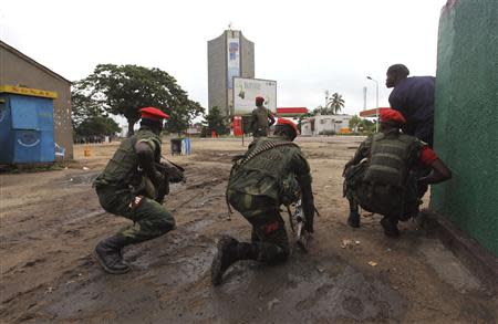 Congolese security officers position themselves as they secure the street near the state television headquarters (C) in the capital Kinshasa, December 30, 2013. REUTERS/Jean Robert N'Kengo