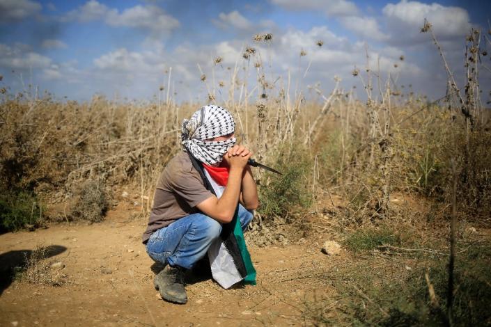 A Palestinian protester, holding a knife, looks on during clashes with Israeli security forces near the border fence between Israel and the Gaza Strip on October 9, 2015 (AFP Photo/Mohammed Abed)