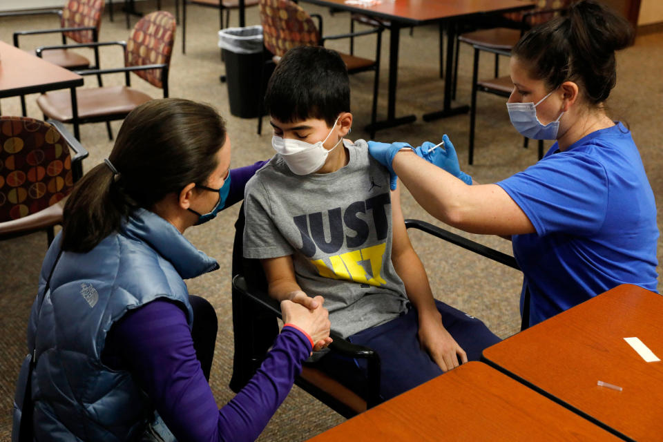 Image: Jamie Blank, left, holds her son, Ari, as he receives a Covid-19 vaccine from a healthcare worker in Bloomfield Hills, Mich., on May 13, 2021. (Jeff Kowalsky / AFP via Getty Images file)