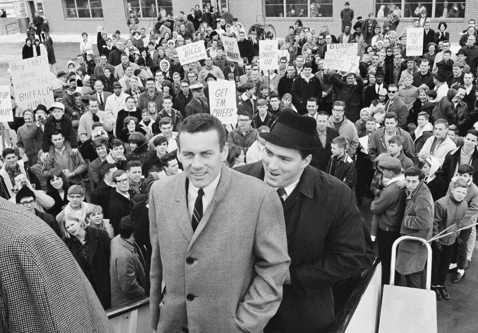 FILE - Len Dawson, front, and Fred Arbanas board the plane as a crowd looks on in Kansas City, Dec. 31, 1966, that will take the Kansas City Chiefs AFL Western division champs to Buffalo, N.Y. where they will play the Eastern champs in the New Year's Day title game. Hall of Fame quarterback Len Dawson, who helped the Chiefs to a Super Bowl title, died Wednesday, Aug. 24, 2022. He was 87.(AP Photo/William Straeter, File)