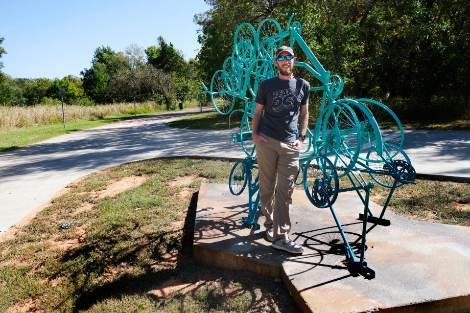 Running/cycling enthusiast and alternative transportation advocate Chase Ray stands next to a sculpture Oct. 13 on Edmond's Spring Creek Trail. Ray and other members of Edmond's Mobility Commission work with city officials to expand ways people who live in the community can make their ways across town.