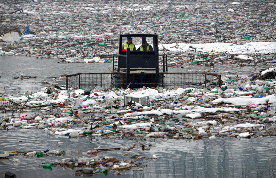 A boat pushes tons of garbage stuck at the foot of the hydro power plant at the Potpecko accumulation lake near Priboj, in southwest Serbia, Friday, Jan. 22, 2021. Serbia and other Balkan nations are virtually drowning in communal waste after decades of neglect and lack of efficient waste-management policies in the countries aspiring to join the European Union. (AP Photo/Darko Vojinovic)