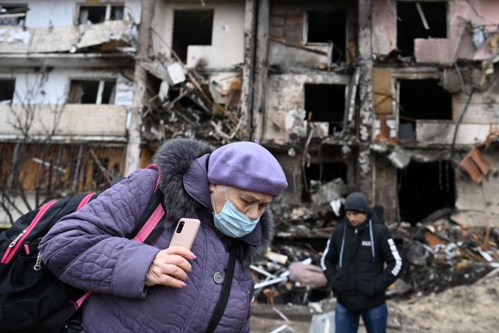 A woman with a backpack walks in front of a damaged residential building at Koshytsa Street, a suburb of the Ukrainian capital Kyiv, where a military shell allegedly hit, on February 25, 2022. - Russian forces reached the outskirts of Kyiv on Friday as Ukrainian President Volodymyr Zelensky said the invading troops were targeting civilians and explosions could be heard in the besieged capital. Pre-dawn blasts in Kyiv set off a second day of violence after Russian President Vladimir Putin defied Western warnings to unleash a full-scale ground invasion and air assault on Thursday that quickly claimed dozens of lives and displaced at least 100,000 people. (Photo by Daniel LEAL / AFP) (Photo by DANIEL LEAL/AFP via Getty Images)