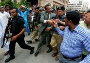 Waseem Akhtar, mayor nominee of Muttahida Qaumi Movement (MQM) political party, escorted by policemen, reaches out to shake hand with party workers after the ballot for mayor outside the Municipal Corporation Building in Karachi, Pakistan, August 24, 2016. REUTERS/Akhtar Soomro