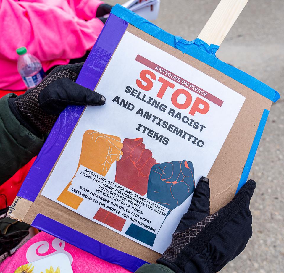 Chloe Longmire holds a flyer talking about the racist items being sold at Antiques on Pierce on Saturday March 4, 2023 in Milwaukee, Wis.