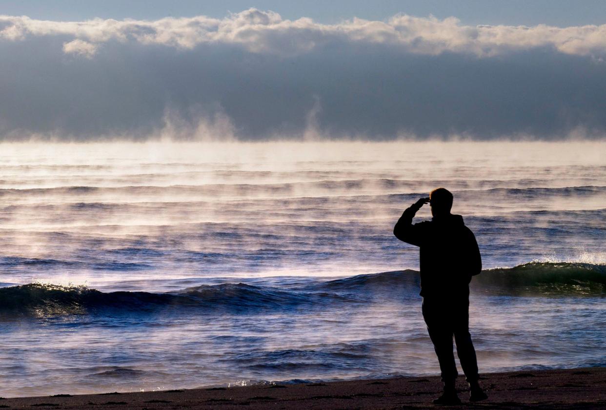 A man looks out to sea as fog rises from the ocean Monday off Palm Beach.