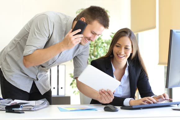 Two smiling business people share good news on a tablet computer.