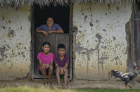 A Macuxi Indigenous family sits in front of their home in the Maturuca community on the Raposa Serra do Sol Indigenous reserve in Roraima state, Brazil, Sunday, Nov. 7, 2021. Bordering Venezuela and Guyana, the territory is bigger than Connecticut and home to 26,000 people from five different ethnicities. (AP Photo/Andre Penner)
