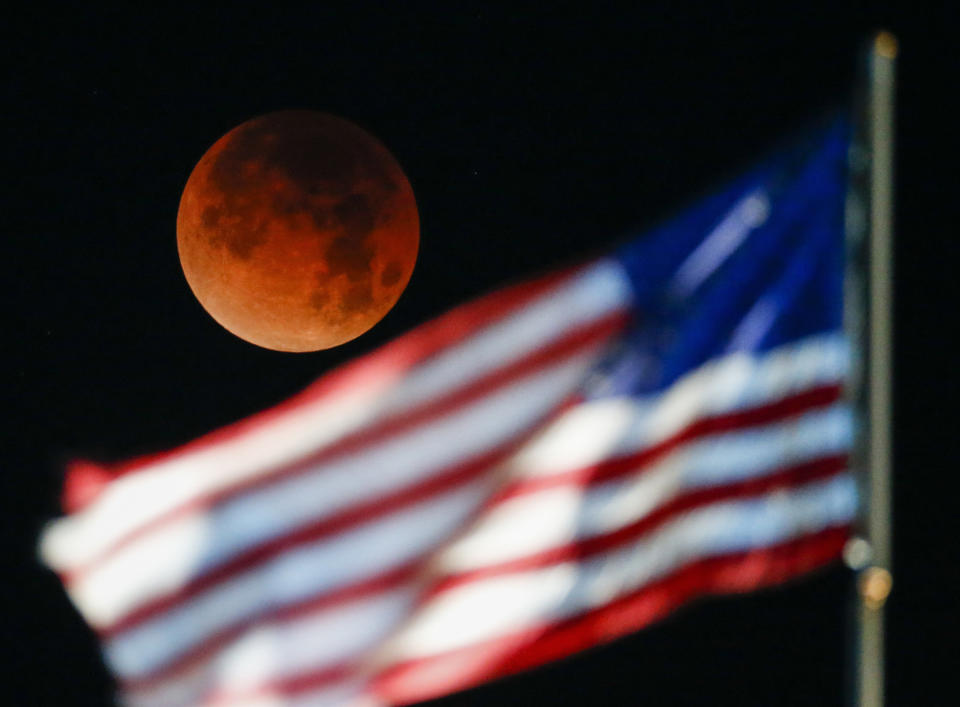 <p>A rare occurrence called a ‘Super Blue Blood Moon’ is seen behind the U.S. flag at Santa Monica Beach in Santa Monica, Calif., Wednesday, Jan. 31, 2018. (Photo: Ringo H.W. Chiu/AP) </p>