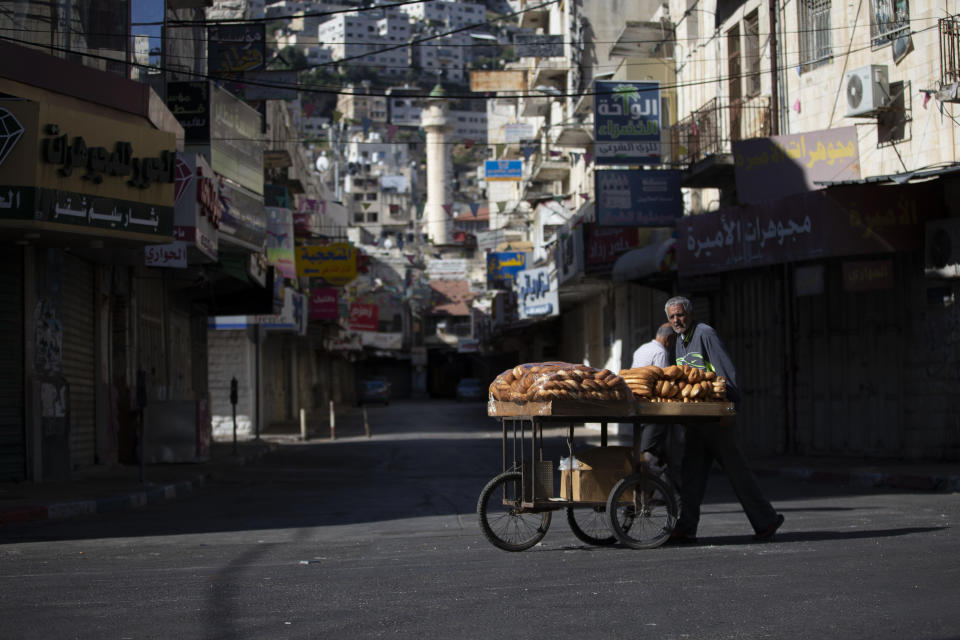 A Palestinian vendor pushes a cart loaded with bread during a general strike, in the West Bank city of Nablus, Tuesday, May 18, 2021. Palestinian leaders are calling for a general strike in Gaza, the West Bank and within Israel to protest against Israel's air strikes on Gaza and the violent confrontations between Israeli security forces and Palestinians in Jerusalem. (AP Photo/Majdi Mohammed)