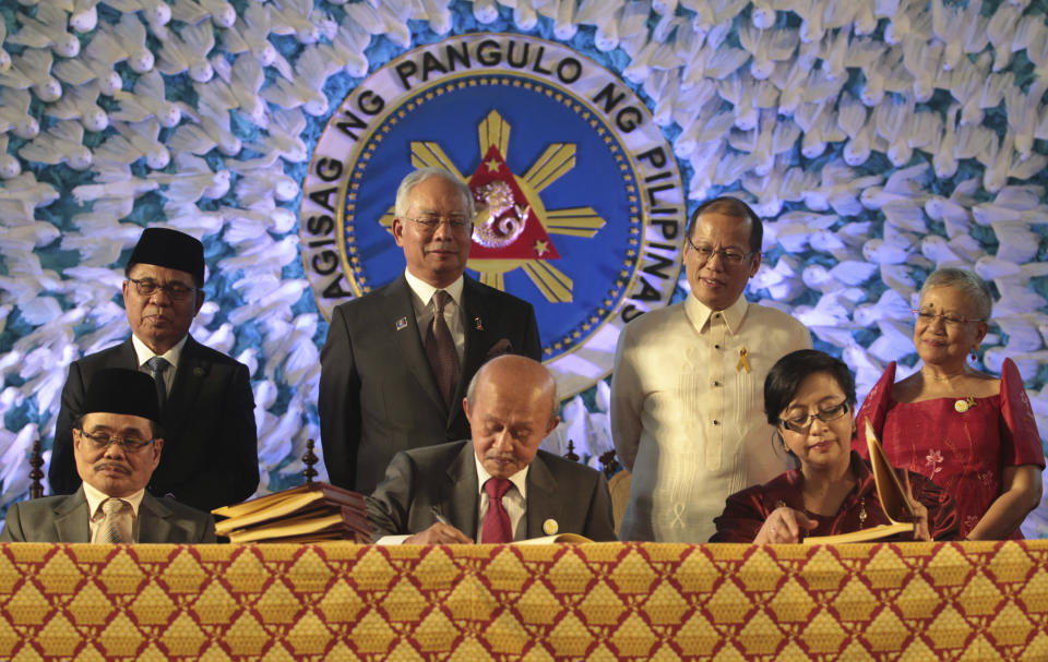 In this handout photo released by the Malacanang Photo Bureau, President Benigno S. Aquino III, back row secon from right, Malaysian Prime Minister Najib Razak, back row second from left, Moro Islamic Liberation Front (MILF) Chairman, Al Haj Murad Ebrahim, back row left, and Secretary Teresita Quintos-Deles, seated left, Presidential Adviser on the Peace Process, back row right, witness the signing of the Comprehensive Agreement on the Bangsamoro (CAB) by MILF chief negotiator Mohagher Iqbal, Datu Tengku Gnafar, seated center, and Miriam Coronel Ferrer, seated right, of the Philippine government in a ceremony at the Malacanang Presidential Palace in Manila, Philippines on Thursday March 27, 2014. The Philippine government signed a peace accord with the country's largest Muslim rebel group on Thursday, the culmination of years of negotiations and a significant political achievement for President Aquino.(AP Photo/Malacanang Photo Bureau, Benhur Arcayan)