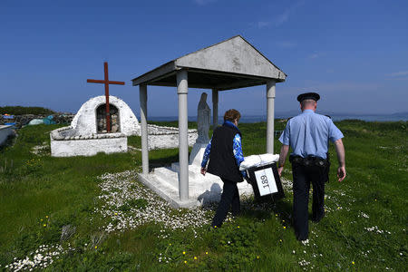 Garda Alan Gallagher and Presiding Officer Carmel McBride carry a polling box, used, a day early, by the few people that live off the coast of Donegal on the island of Inishbofin, to vote in the referendum on liberalising abortion law, in Inishbofin, Ireland May 24, 2018. REUTERS/Clodagh Kilcoyne