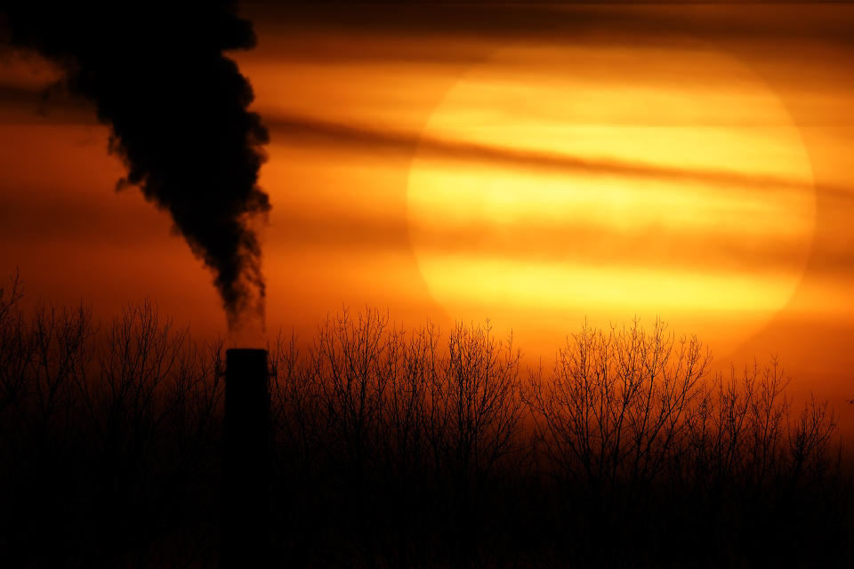 FILE - In this Monday, Feb. 1, 2021 file photo, emissions from a coal-fired power plant are silhouetted against the setting sun in Independence, Mo. Dozens of European lawmakers, business executives and union leader called Tuesday for the United States to cut its greenhouse gas emissions by 50% in the coming decade compared with 2005 levels. (AP Photo/Charlie Riedel)