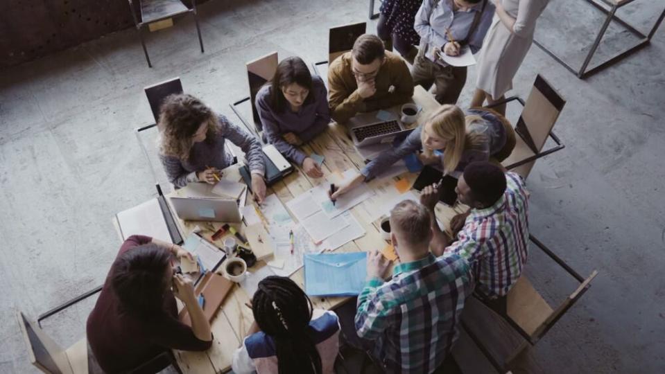 Top view of mixed race business team sitting at the table at loft office and working. Woman manager brings the document